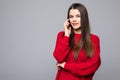 Attractive happy woman has dreamy expression, talks via cell phone, enjoys conversation with friend, wears red sweater, poses over Royalty Free Stock Photo