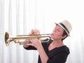 Attractive woman with hat playing the trumpet