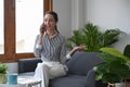 Attractive woman having cell phone conversation while sitting on couch at home. Royalty Free Stock Photo