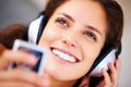 Attractive woman with headphones. Closeup of attractive smiling woman listening to music on her mp3 player and looking Royalty Free Stock Photo