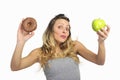 Attractive woman holding apple and chocolate donut in healthy fruit versus sweet junk food temptation Royalty Free Stock Photo