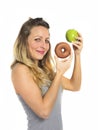 Attractive woman holding apple and chocolate donut in healthy fruit versus sweet junk food temptation Royalty Free Stock Photo