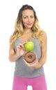 Attractive woman holding apple and chocolate donut in healthy fruit versus sweet junk food temptation Royalty Free Stock Photo