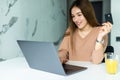 attractive woman holding credit card near laptop in kitchen Royalty Free Stock Photo