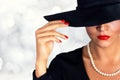 Attractive woman holding glass of white wine.Portrait of a beautiful girl wearing black hat. Royalty Free Stock Photo