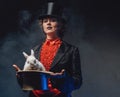 Attractive woman holding a top hat there is a white rabbit in smoke