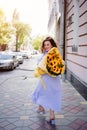 attractive woman with huge bouquet of decorative sunflowers walks along city