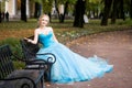 Attractive woman in long blue dress sitting in bench in park Royalty Free Stock Photo