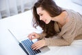 Attractive woman lying on bed and using laptop Royalty Free Stock Photo