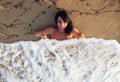 Attractive woman is lying under a cover of sea foam