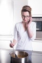 Attractive woman in modern ktchen cooking and on the phone