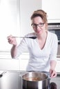 Attractive woman in modern ktchen cooking and tasting