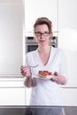 Attractive woman in modern ktchen eating strawberry cake