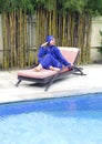 Attractive woman in a Muslim swimwear burkini on a beach plank bed near the pool Royalty Free Stock Photo