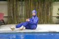 Attractive woman in a Muslim swimwear burkini on a pool side in a tropical garden Royalty Free Stock Photo