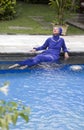 Attractive woman in a Muslim swimwear burkini sits on the edge of the pool Royalty Free Stock Photo