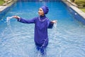 Attractive woman in a Muslim swimwear burkini splashes water in the pool Royalty Free Stock Photo