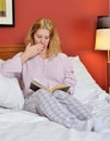 Attractive woman in pajamas in bed reading a juicy book Royalty Free Stock Photo