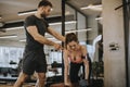 Attractive woman and a personal trainer with weight training at gym Royalty Free Stock Photo