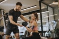 Attractive woman and a personal trainer with weight training at gym Royalty Free Stock Photo