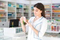 Attractive woman pharmacist with gentle hands holding a small jar with drug or vitamins in a pharmacy Royalty Free Stock Photo