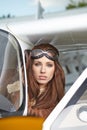 Attractive woman pilot wearing sunglasses standing in the sunshine on an airfield resting against her small private airplane Royalty Free Stock Photo