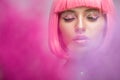attractive woman with pink hair and makeup with glitter standing in pink smoke