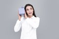 Attractive woman with present box posing with surprised face expression on gray background. Girl holding gift decorated Royalty Free Stock Photo