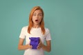 Attractive woman with present box posing with surprised face expression on gray background. Girl holding gift decorated Royalty Free Stock Photo