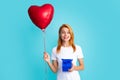 Attractive woman with present box posing with surprised face expression on gray background. Girl holding gift decorated Royalty Free Stock Photo