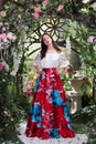 Attractive woman in red skirt in floral garden. Fairy tale Royalty Free Stock Photo