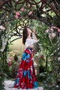 Attractive woman in red skirt in floral garden. Fairy tale Royalty Free Stock Photo