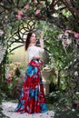 Attractive woman in red skirt in floral garden. Fairy tale Royalty Free Stock Photo