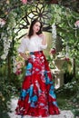 Attractive woman in red skirt in floral garden. Fairy tale Royalty Free Stock Photo