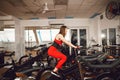 Attractive woman in a red sports suit in gym, riding on speed stationary bike. Healthy lifestyle Royalty Free Stock Photo