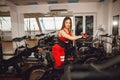 Attractive woman in a red sports suit in gym, riding on speed stationary bike. Healthy lifestyle Royalty Free Stock Photo