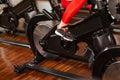 Attractive woman in a red sports suit in gym, riding on speed stationary bike. Women`s legs close up Royalty Free Stock Photo