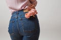 Attractive woman`s butt in a blue jeans and fresh roses living coral color in a back pocket on a light gray background