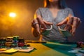 Attractive woman shuffles poker cards in a casino on the background of a table and chips. Concept of poker game Royalty Free Stock Photo