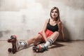 Attractive woman sitting on the floor in roller skating looking