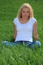 Attractive woman sitting on green meadow Royalty Free Stock Photo