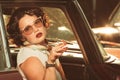 Attractive woman sitting in retro car and she smokes a cigarette Royalty Free Stock Photo