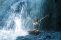 Attractive woman sitting at rock in yoga pose for spiritual relaxation serenity and meditation at stunning beautiful waterfall and Royalty Free Stock Photo