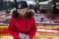 Attractive woman in ski suit, with helmet and ski goggles putting on gloves in a ski-resort Royalty Free Stock Photo