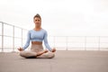 Attractive woman practicing yoga and sitting in lotus position outdoor. Royalty Free Stock Photo