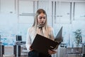 Attractive woman standing alone at the office and hold folder for paper documents Royalty Free Stock Photo