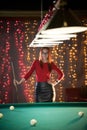 An attractive woman standing in billiard club holding a cue. Posing for the camera Royalty Free Stock Photo
