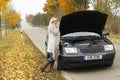 Attractive woman standing helpless beside her broken car Royalty Free Stock Photo
