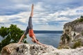 Attractive woman standing on the rock and doing yoga exercises above river. Royalty Free Stock Photo