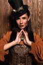 Woman with steampunk makeup touching medallion on wooden